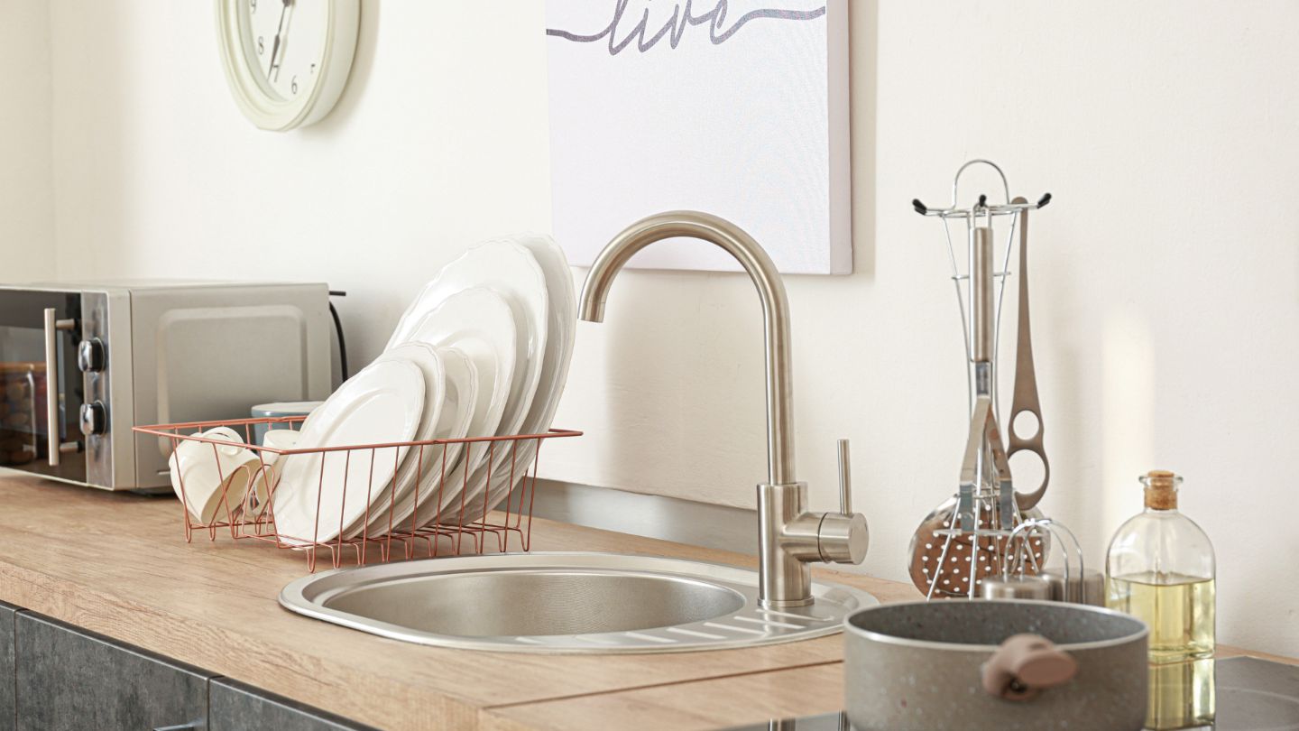 Clean and organized kitchen with spotless countertops, stainless steel sink, and neatly arranged dishes