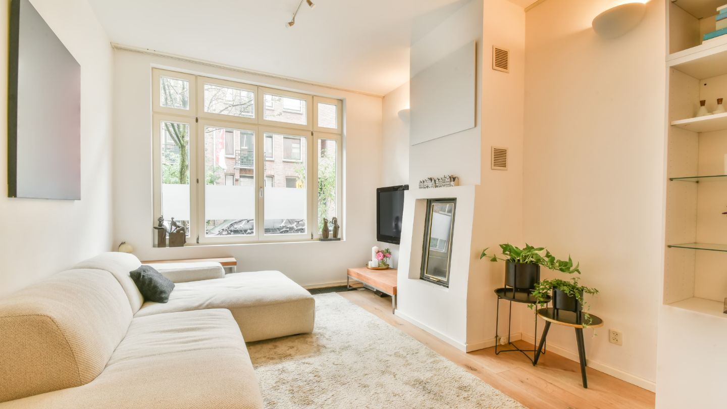 Clean and organized living room with sectional sofa, hardwood floors, and natural lighting