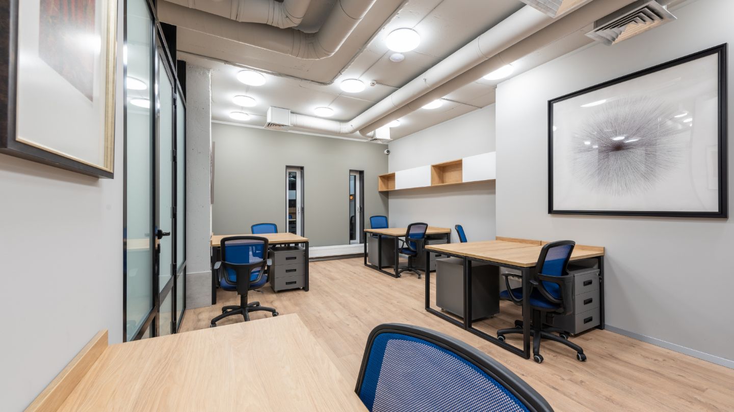 Modern professional office workspace with blue ergonomic chairs, wooden desks, and clean organized environment