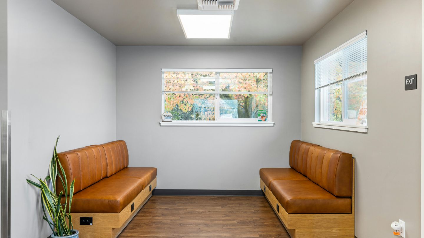 Modern professional waiting room with brown leather bench seating, large windows with blinds, and clean minimalist design